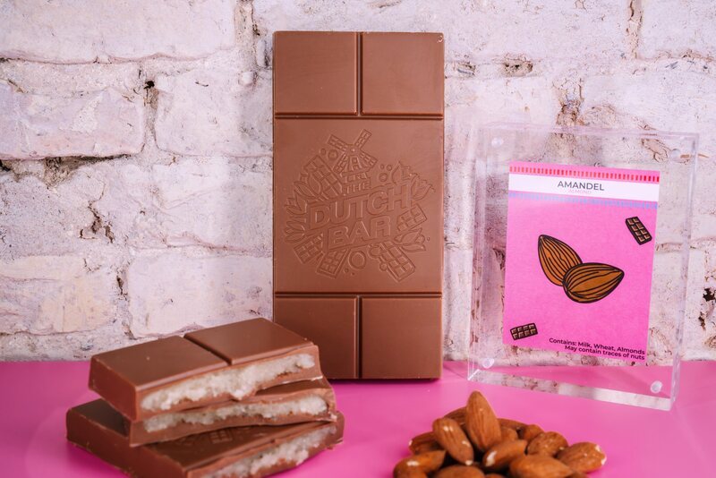 The almond paste bar broken open to show its white filling, next to almonds and the pink flavour card