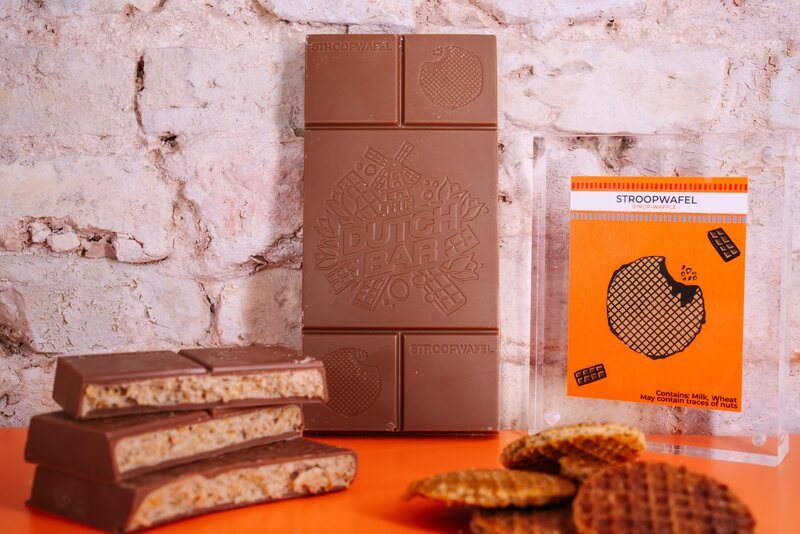 The stroopwafel bar with its embossed windmill logo, next to loose stroopwafels and the orange flavour card