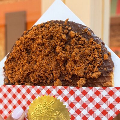 A chocolate-dipped giant stroopwafel covered in crumbled Biscoff speculoos biscuit