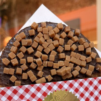 A chocolate-dipped giant stroopwafel covered in soft caramel fudge cubes
