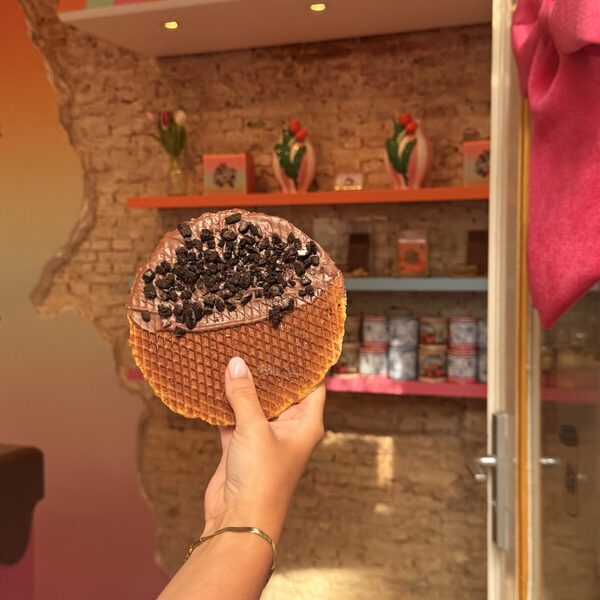 An Oreo stroopwafel held in the doorway, with tulip vases on the orange shelf and Delft blue tins on the shelf below